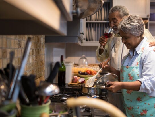 Man having wine while woman preparing food